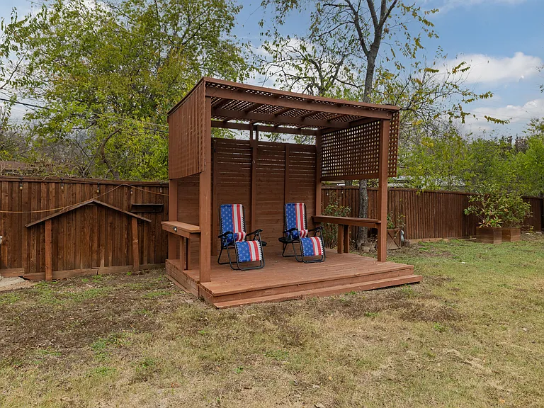 Relax under the backyard pergola in the fully-fenced yard, featuring shaded seating and lounge chairs_perfect for reading, sipping coffee, or unwinding outdoors in a peaceful, private setting.