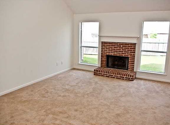 Large living room is bright and cheery with fresh paint, new carpet and a wall of windows overlooking the fenced backyard.