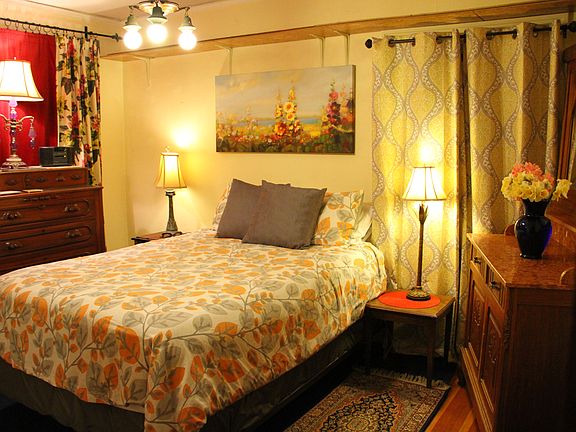 Comfortable queen bed surrounded by hand-carved antiques that reflect the original charm of this 1925 bungalow, where timeless charm blends with modern ease.