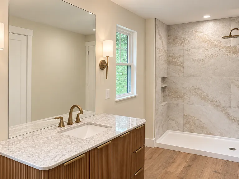A spa-inspired bathroom features a modern high-end designer vanity, elegant champagne plumbing fixtures, a luxurious rain shower with stylish large-format tile, and a private toilet nook designed for comfort and privacy.
