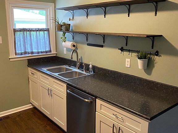 Kitchen featuring open shelving on wall above the sink and dishwasher.