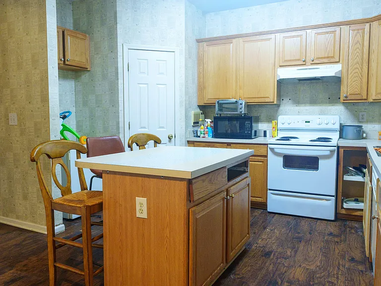 Eat-in kitchen with a center island, ample wood cabinetry, and full-size electric range plus countertop microwave.