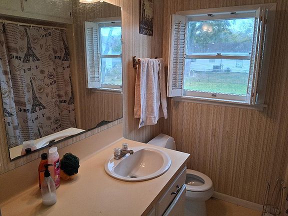 Bath with a tub and shower. The shower curtain can be seen in the mirror.