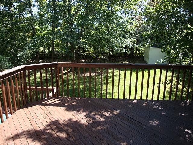 Deck off of kitchen viewing fenced wooded private back yard.