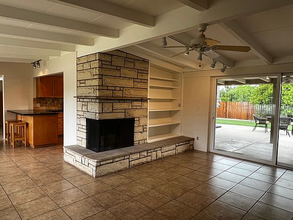 Upon walking through the front door, the mid-century style of the home is highlighted by an open floor plan, a wood-burning fireplace (with gas), open shelves, and a view of the backyard.
