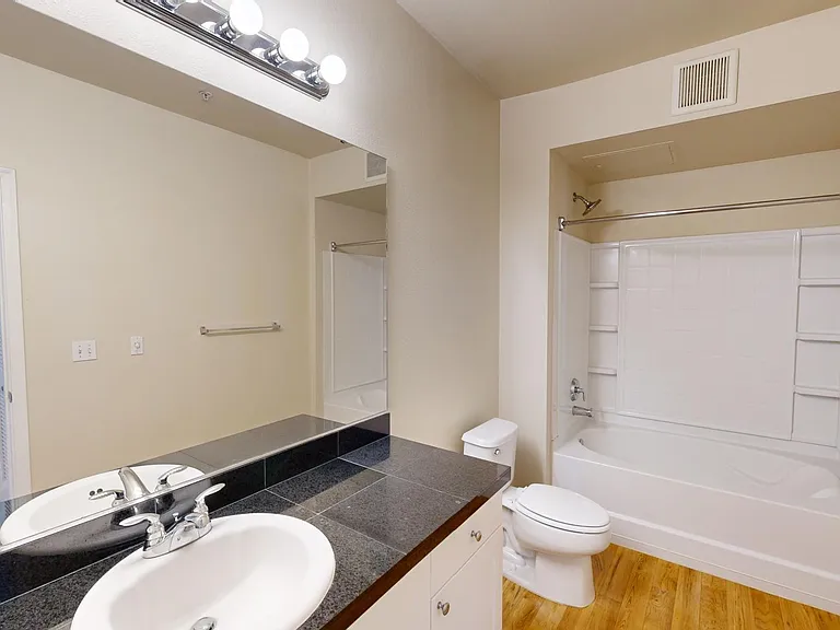 Apartment bathroom with large soaking tub and wood-style flooring.