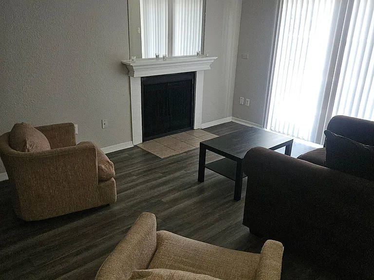 Living room with fireplace mantel and oversized wall mirror, plus sliding glass doors for easy outdoor access.