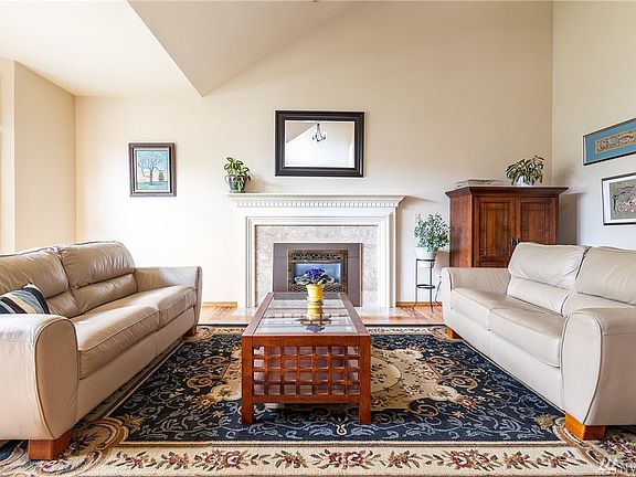 Formal living room features vaulted ceiling, fireplace with marble facing and elegant white mantel with large bay window overloo