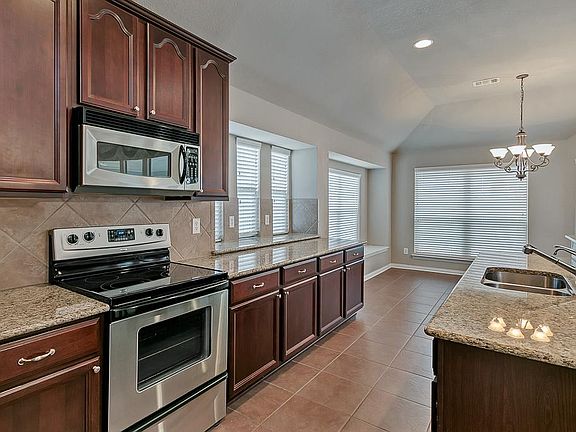 Bright kitchen has granite countertops, under-mount sink, ceramic cooktop, ceramic tile floors and loads of storage. It opens to the family room and breakfast nook which is surrounded by windows, providing plenty of natural light.