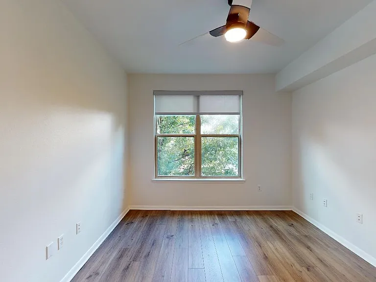 Spacious apartment bedroom with wood-style flooring.
