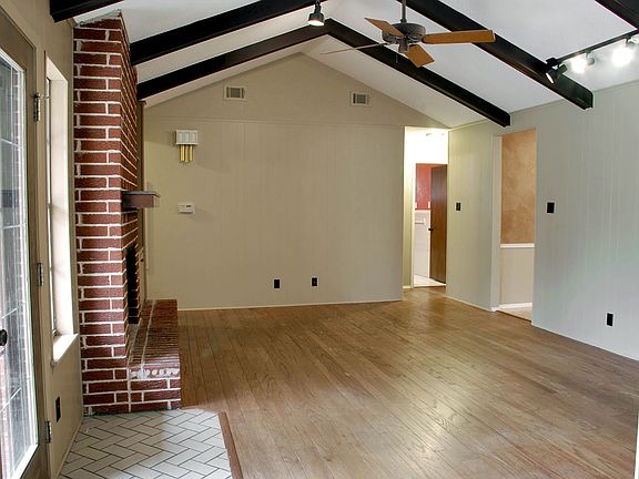 Living room features wood floors, fireplace and vautled ceiling.