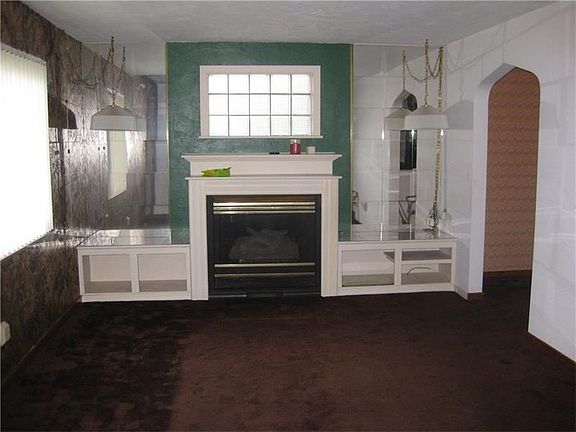 Living Room with fireplace and built-ins.  Hardwood under carpet. Large archway connects to Dining Room and slider to deck.