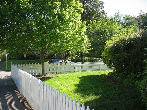 White picket fence borders large front yard.