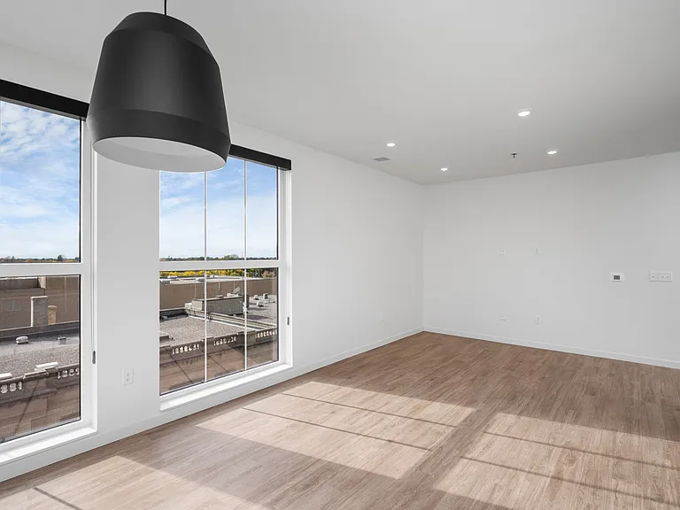 Bright and spacious living area with large windows offering stunning views, modern wood flooring, and sleek lighting fixtures. Bright and spacious living area with large windows offering stunning views, modern wood flooring, and sleek lighting fixtures.