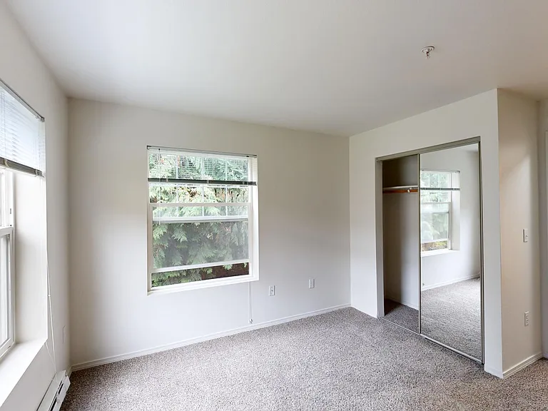 Spacious apartment bedroom with plush carpet flooring.