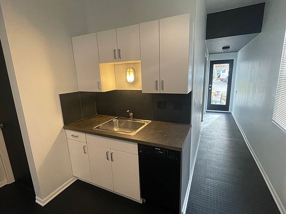 Kitchen clean up, sink and dishwasher w/ concrete countertop and slate backsplash.