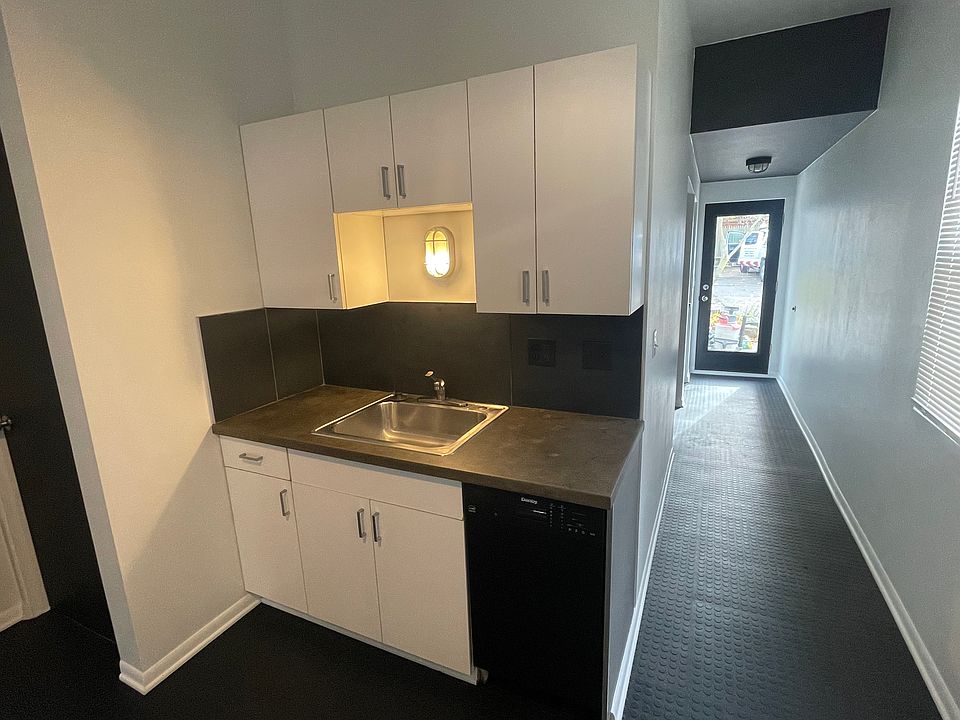 Kitchen clean up, sink and dishwasher w/ concrete countertop and slate backsplash.
