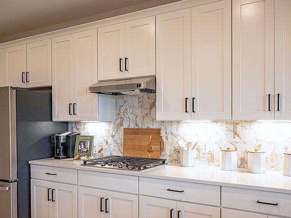 Kitchen with white cabinetry and accent patterned backsplash and gas range