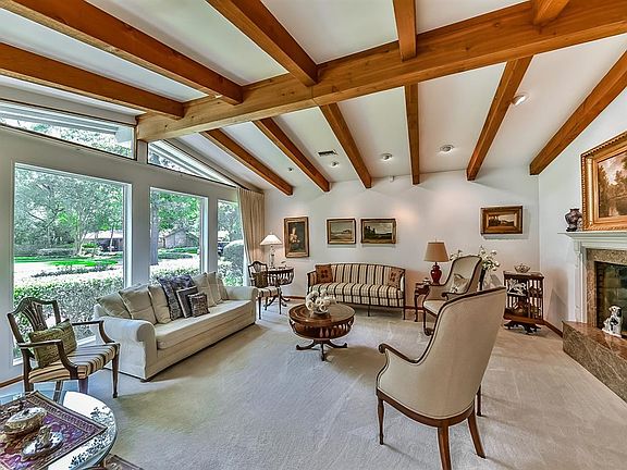 Formal living room boasts wood beams that continue into the den. Triangular transom windows add to the interest of this space.