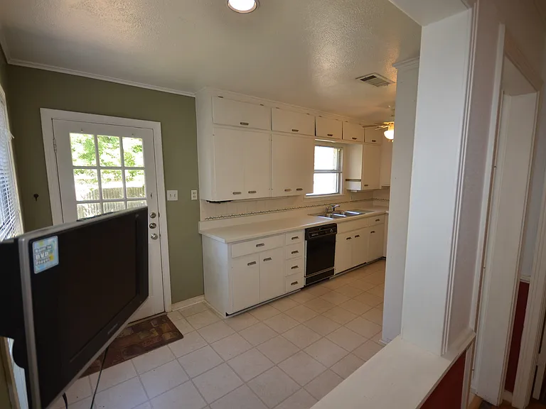 Kitchen space featuring white cabinetry with silver-tone hardware, a white countertop, and a white tile backsplash.
