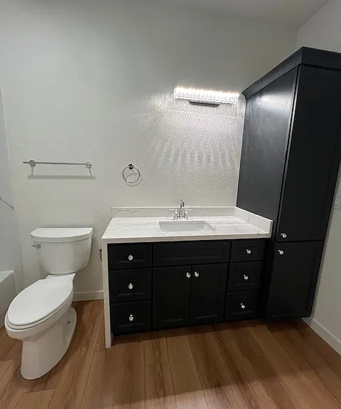 View of the bathroomnew toilet sink faucets and counter and navy blue cabintry dfrom in fron tof the hookups for the washer and dryer.