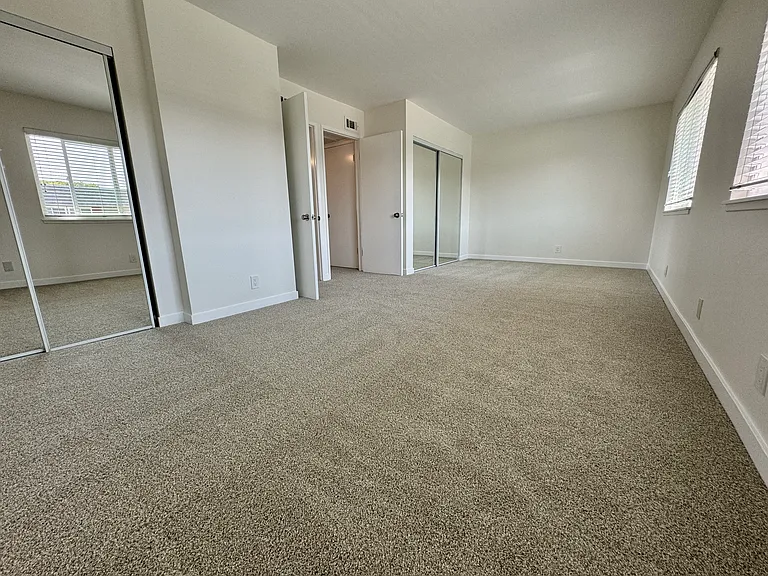 Spacious master bedroom (2 bedrooms converted to 1) with new wall to wall carpet, mirrored wardrobe doors and paint!