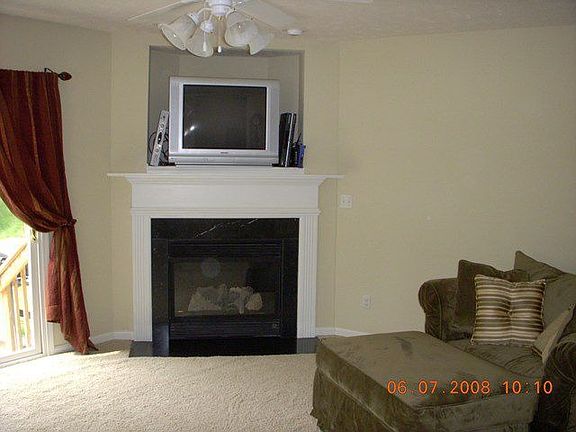 Living room with corner fireplace and sliders to patio with wooded views.