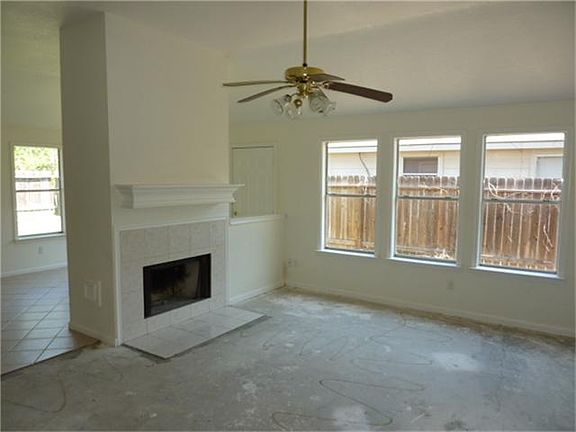 Den with fireplace, high ceiling and ceiling fan