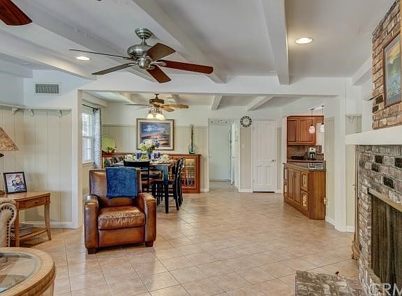 Open floor plan, beam ceilings, wainscoting and a rustic fireplace with tile floors in the family room