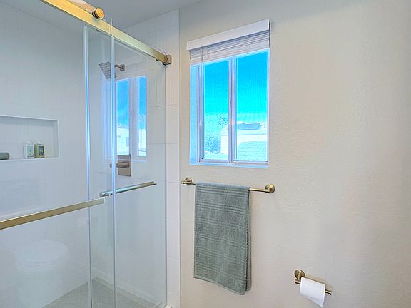 Newly remodeled primary bath with new shower, new tile, and new plumbing and lighting fixtures.