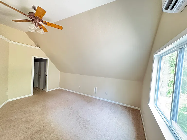 The spacious primary bedroom offers partial vaulted ceilings, dedicated heating and cooling, and ample space for both a bedroom suite and a cozy reading or sitting area.