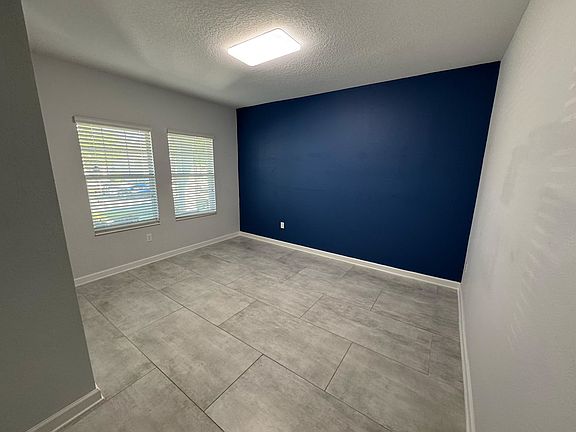 Flex Room or Office _ Tiled room with navy accent wall and ample natural light, ideal for a home office or studio.