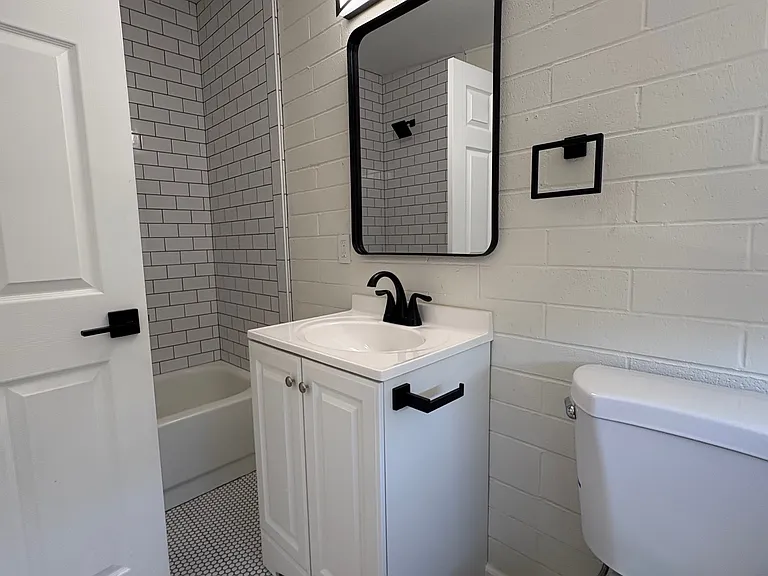 Bathroom with shower / tub combo, new penny tile and subway tile, toilet and vanity.
