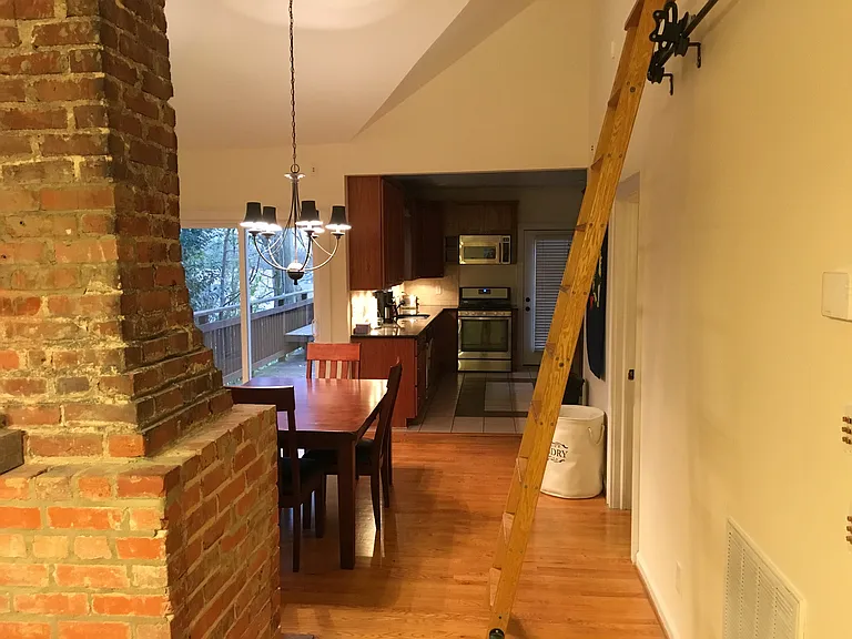 After entering front door or leaving the second bedroom, living room is to the left with dining and kitchen ahead, ladder up to attic storage area.
