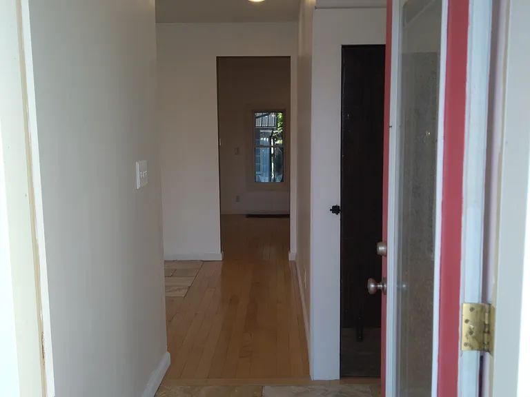View of the inside of the house from the foyer. Closet on the right. Dining room at the end of the hall with the living room to the left past the partial wall.