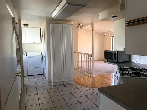 Kitchen has a gas stove, opens to living and dining areas.