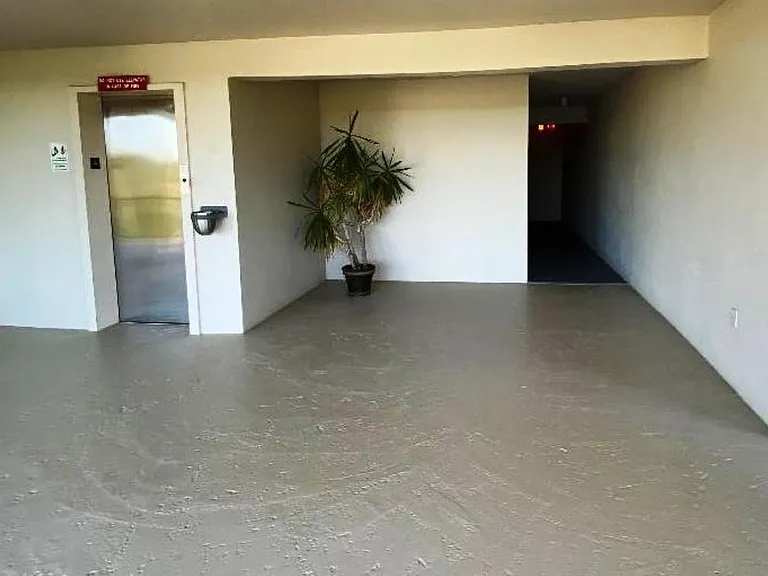 4th-floor center landing with elevator entrance, walkway to laundry room at rear of building.