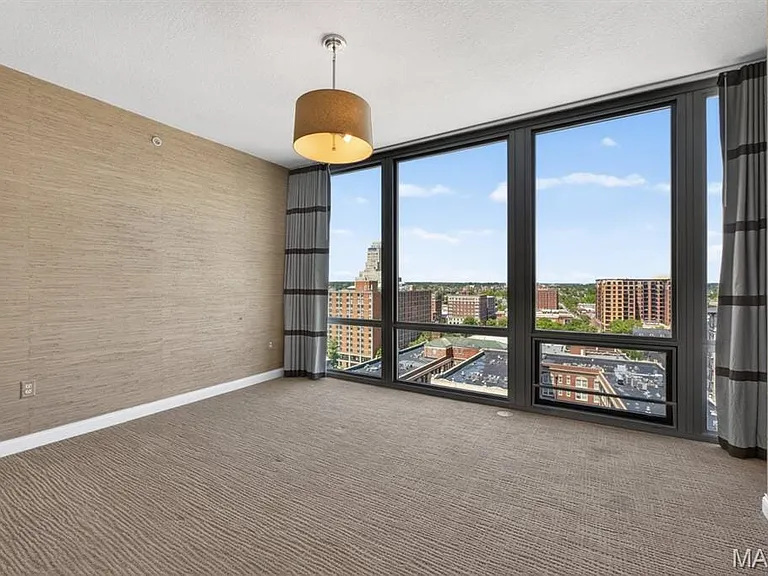 Floor-to-ceiling windows with dark frames showcase the surrounding cityscape