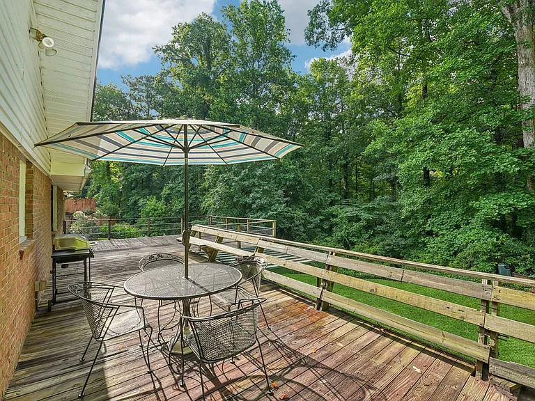 This enchanting deck overlooks a lush wooded backdrop, creating a private outdoor retreat perfect for dining, relaxing, and enjoying the gentle magic of nature.
