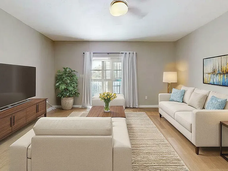 Inviting living room with contemporary beige sofa, elegant artwork, and lush green plant, perfect for relaxation and entertaining.