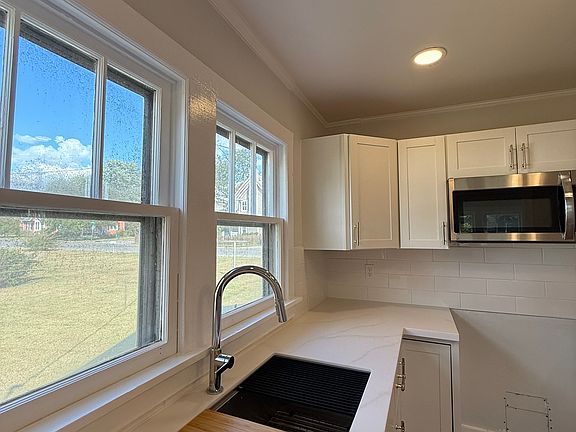 Double basin stainless steel sink with spray faucet and cutting board.