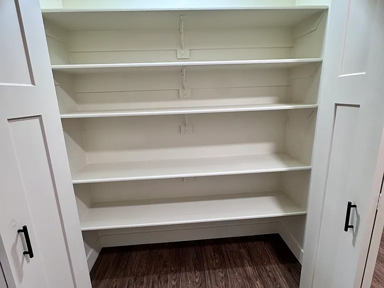 Spacious pantry with built-in shelving, offering ample storage and easy organization.