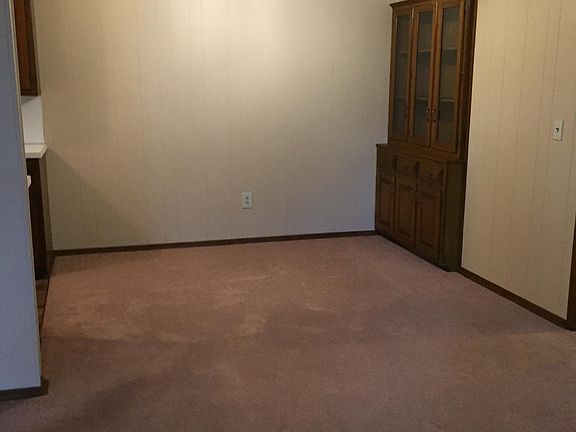 Dining room with built in china cabinet and ceiling fan adjacent to kitchen.