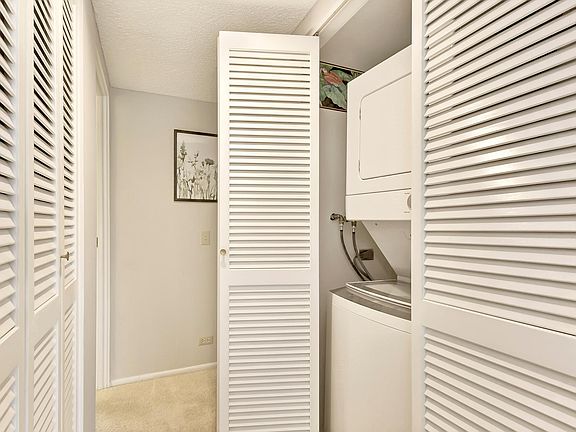 Handy stacked washer dryer located in central hallway. Linen closet on left