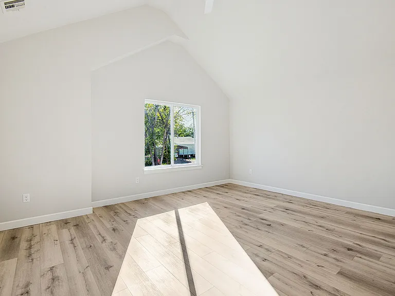 Spacious primary suite with vaulted ceiling and ceiling fan