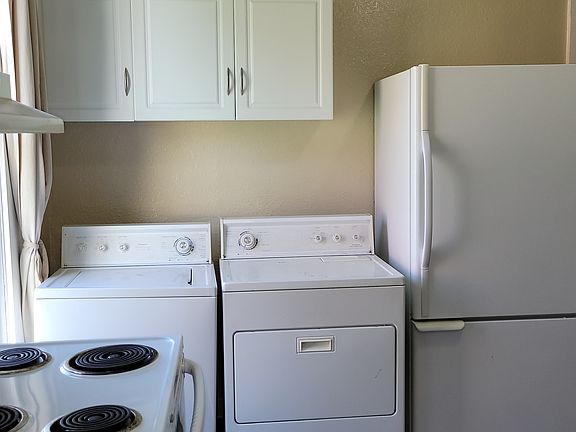 Kitchen with full-sized washer and dryer and refrigerator with bottom freezer. Door leads to deck.