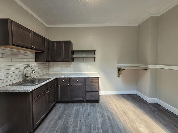 Kitchen w/ open shelving and a custom, wood stained high top, wall mounted countertop space
