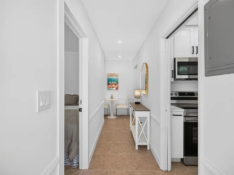 Efficient hallway nook with bistro seating, storage console, and easy access to the kitchen with stainless appliances.