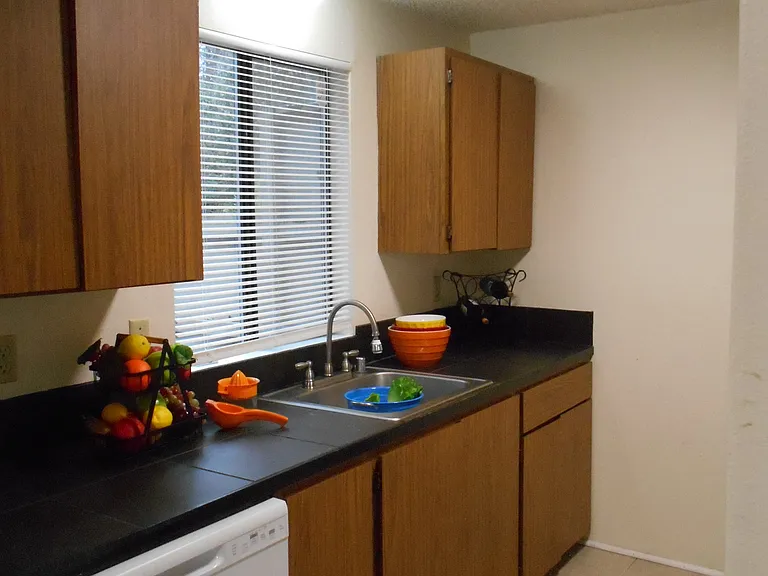 Galley style kitchen comes equipped with a range, refrigerator, and dishwasher.
