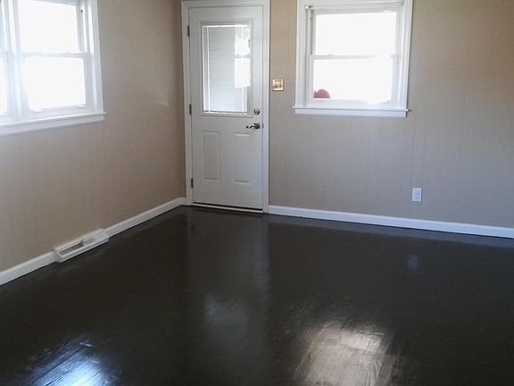 large dining room with hardwood floors and back door that leads to a protected car port and patio in back.